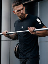 URBAN WOLFS model lifting barbell in men's dry-fit black tees, fitted moisture-wicking workout shirt with sleeve stripes